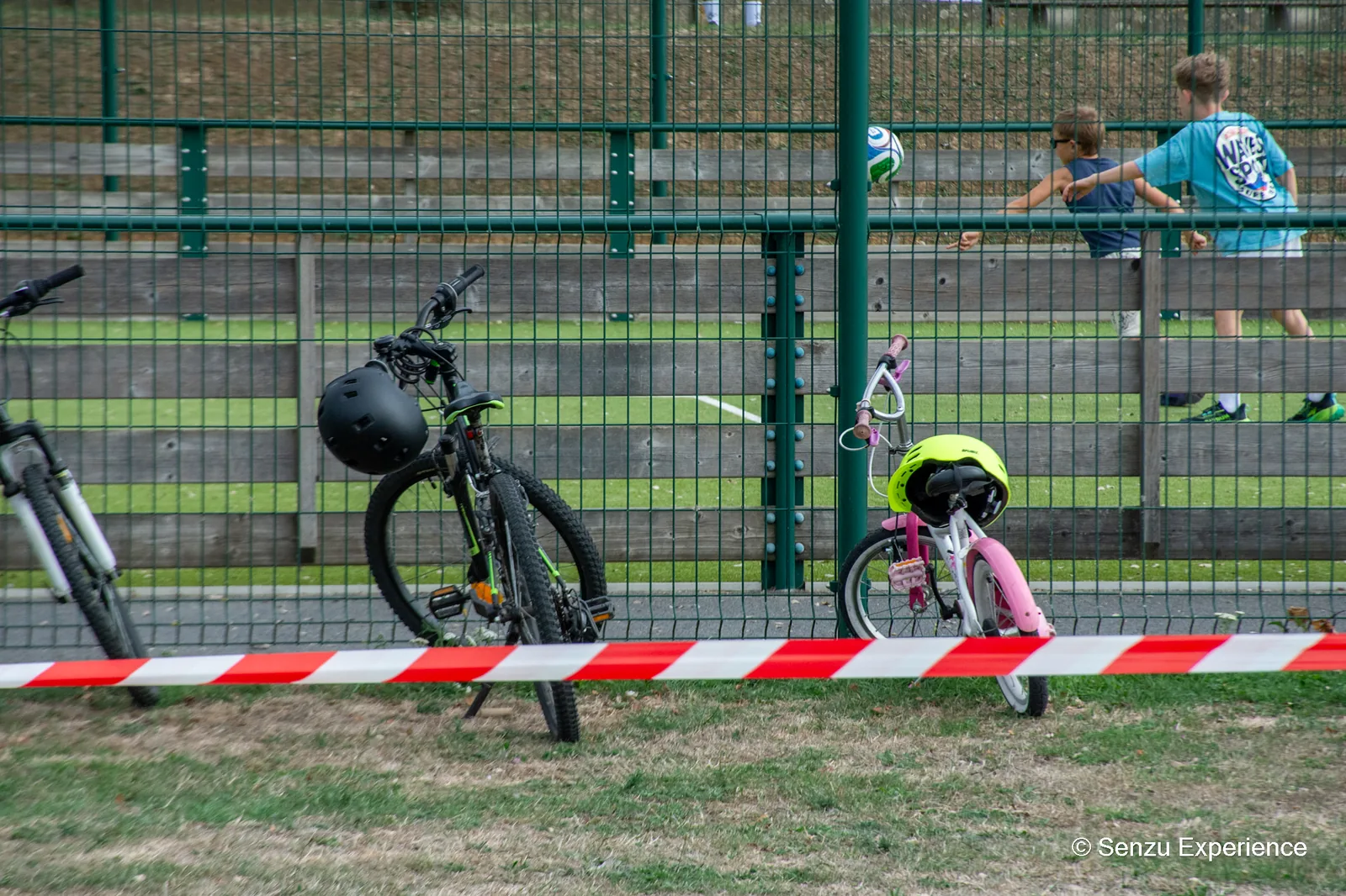 V&eacute;los et casques d'enfants align&eacute;s le long du terrain, en attente du passage sur le parcours
